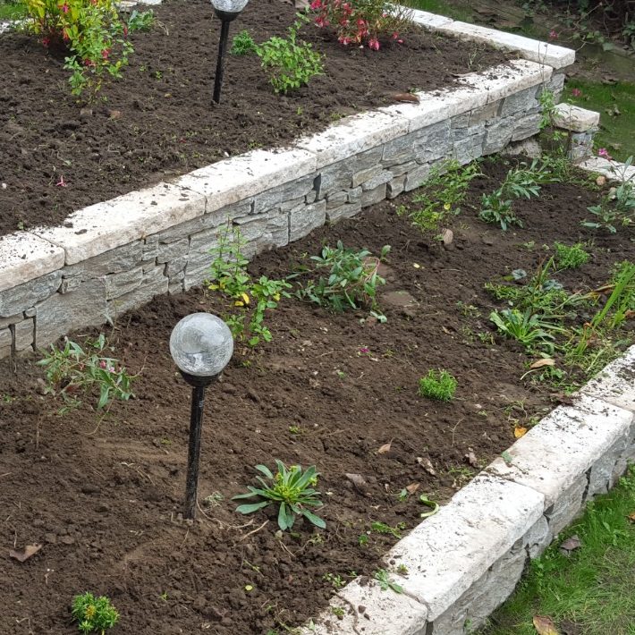 Jardin en terrasses avec des plantes et des lanternes solaires.